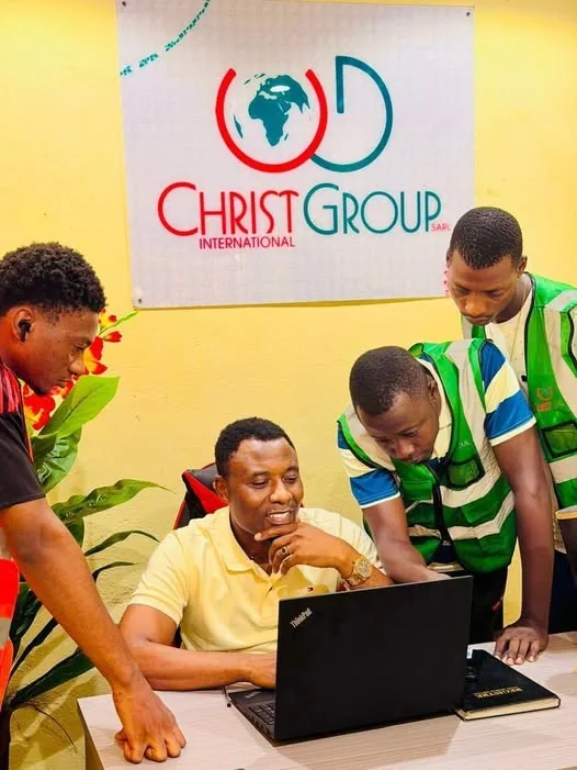 Des membres de l'équipe Christ Group travaillant ensemble autour d'un ordinateur portable