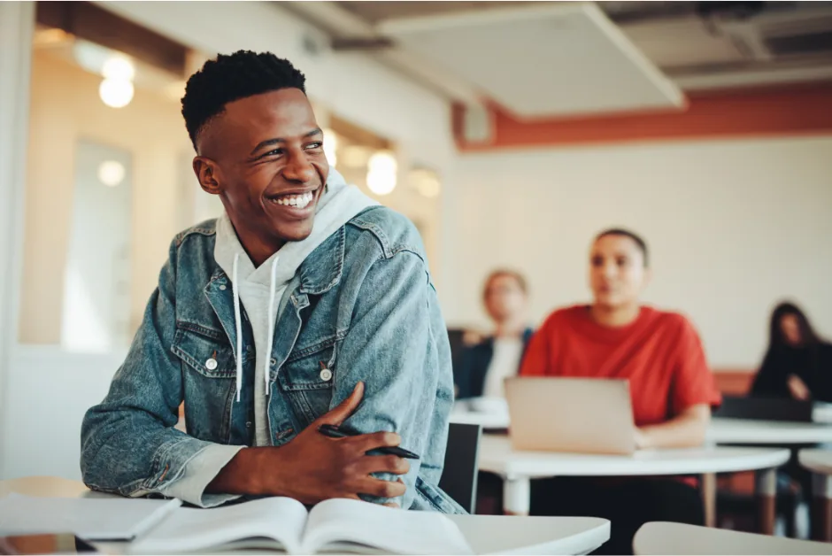 Étudiant souriant à son bureau dans une salle de classe