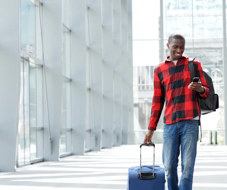 Voyageur souriant avec sa valise et son téléphone à l'aéroport