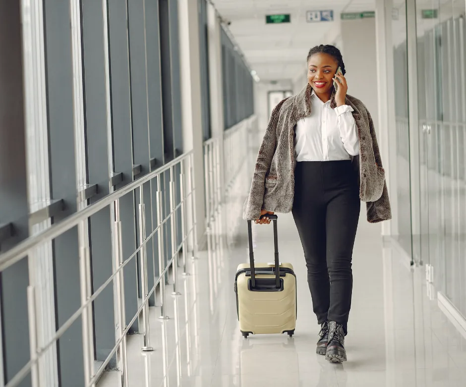Voyageuse souriante avec sa valise dans un couloir d'aéroport
